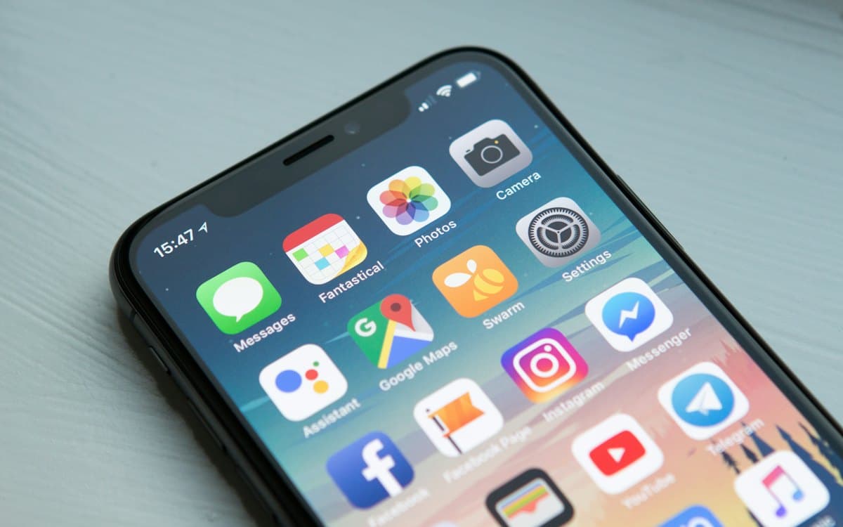 Un iPhone tenu en main devant un écran